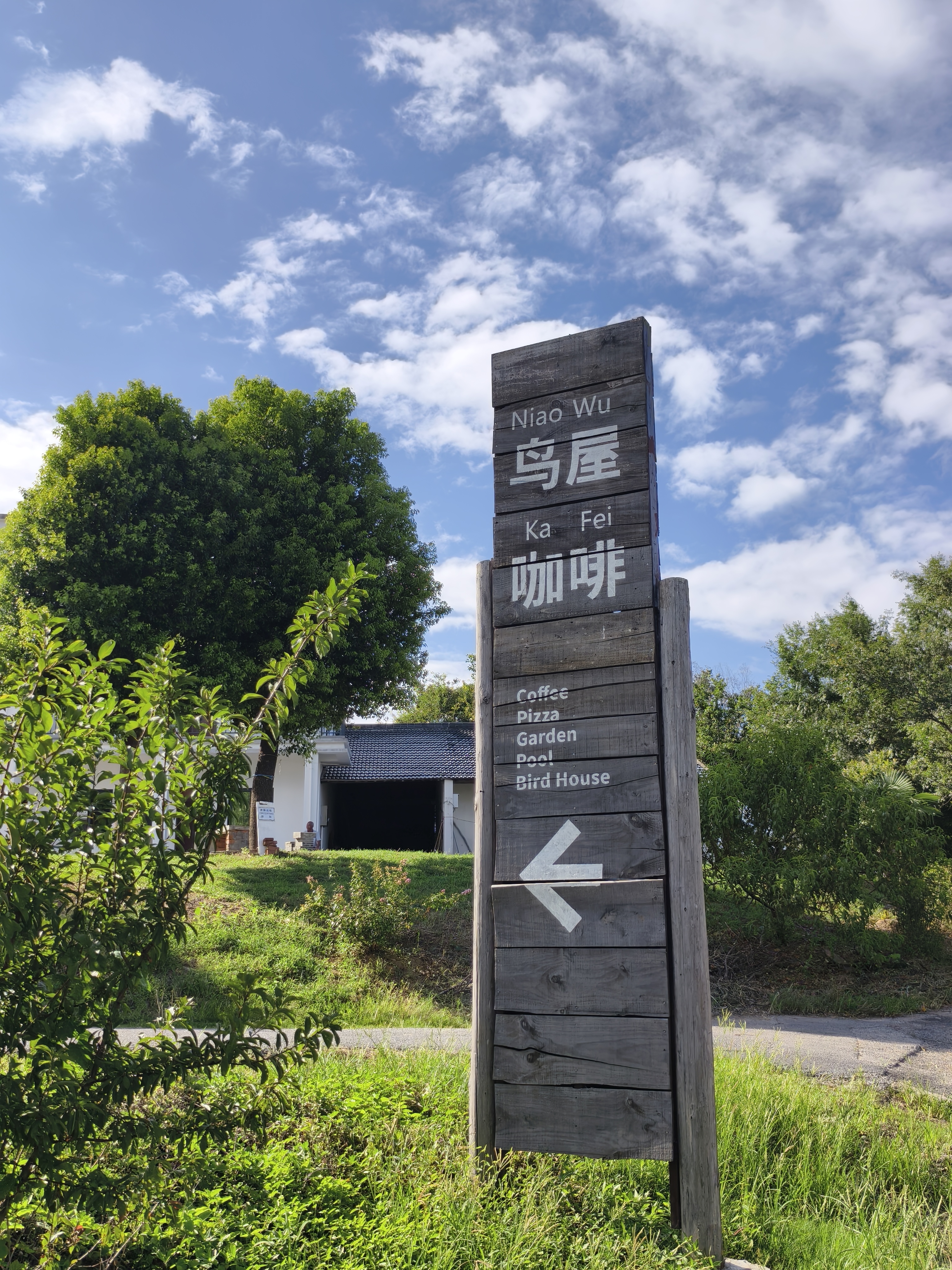 乡间路口写着鸟屋咖啡和向右箭头的木牌